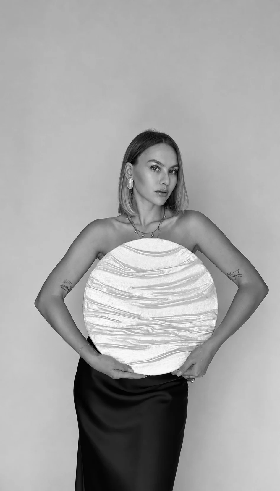 Anastasia holding a round white textured artwork